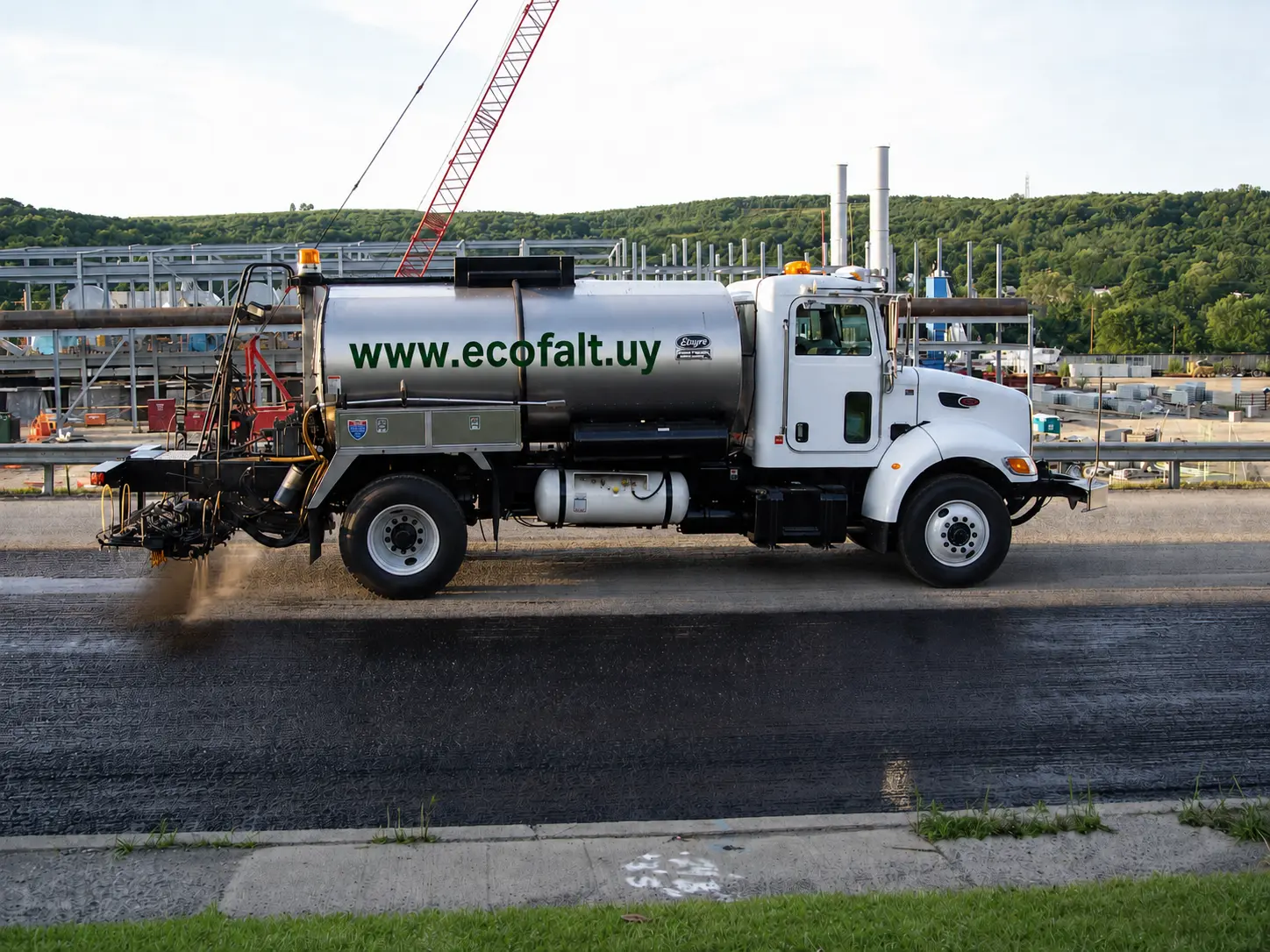 Camión regador con la dirección www.ecofalt.uy trabajando sobre una superficie vial